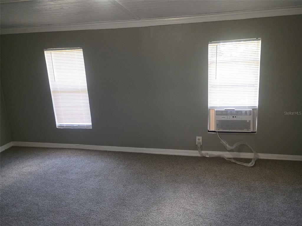 A room with gray walls, gray carpeting, two windows with blinds, and a window air conditioner — 861 SADDLEWOOD BOULEVARD, LAKELAND, FL
