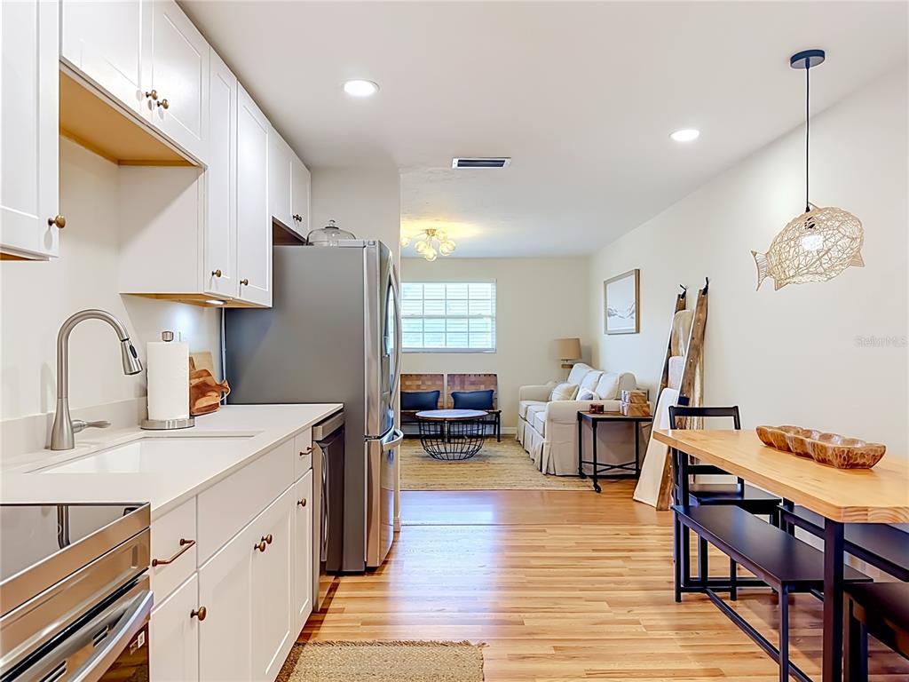 A kitchen with white cabinets and stainless appliances opens into a living and dining area — 202 PEACOCK LANE UNIT B, HOLMES BEACH, FL
