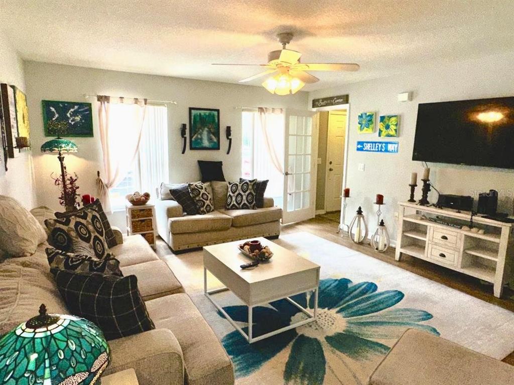 A living room features a large floral area rug, a white coffee table, and a television — 891 N REMBRANDT WAY, INVERNESS, FL
