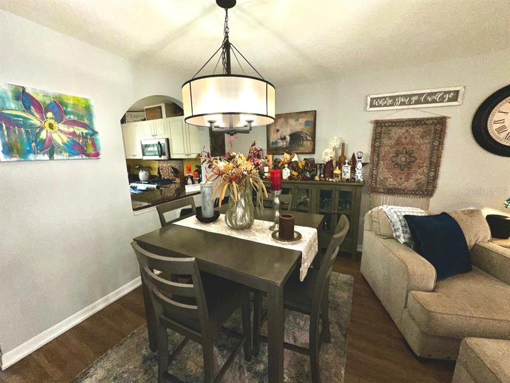 A dining area features a dark wood table, a chandelier, and an arched kitchen pass-through — 891 N REMBRANDT WAY, INVERNESS, FL