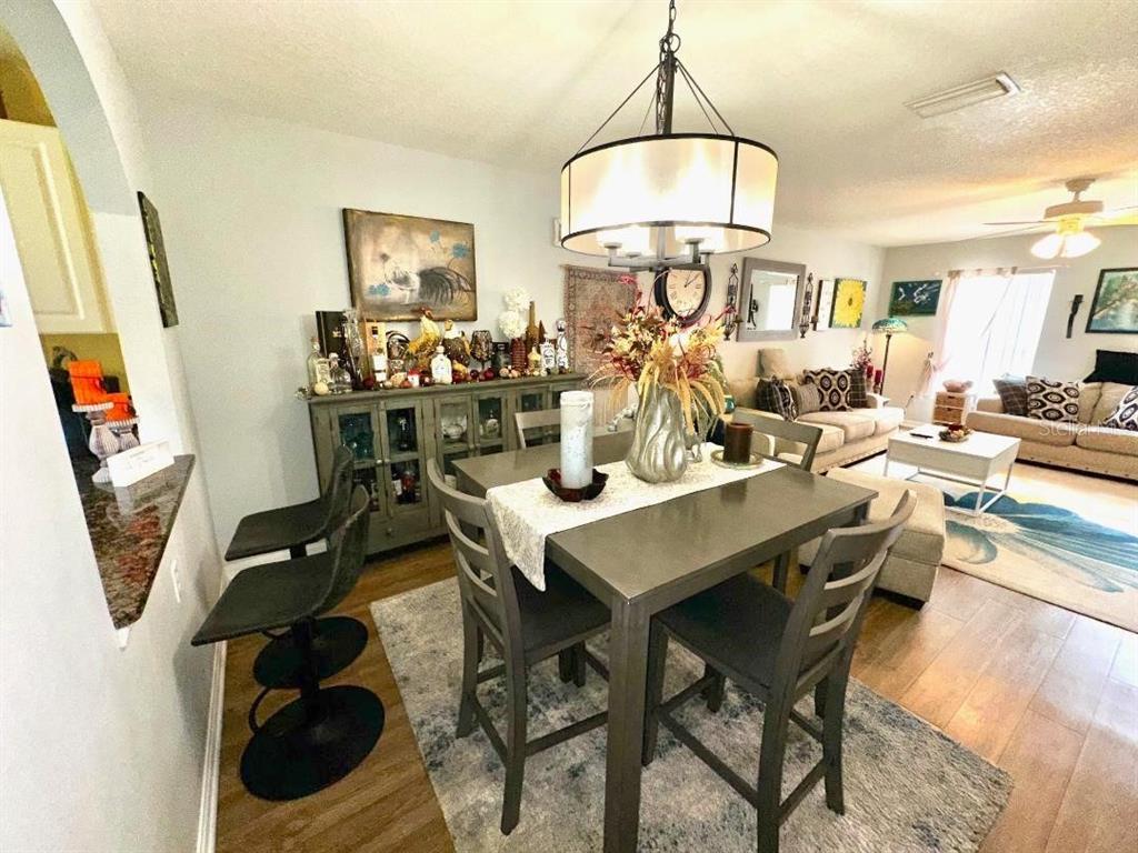A dining area with a gray table and chairs sits adjacent to a living room — 891 N REMBRANDT WAY, INVERNESS, FL
