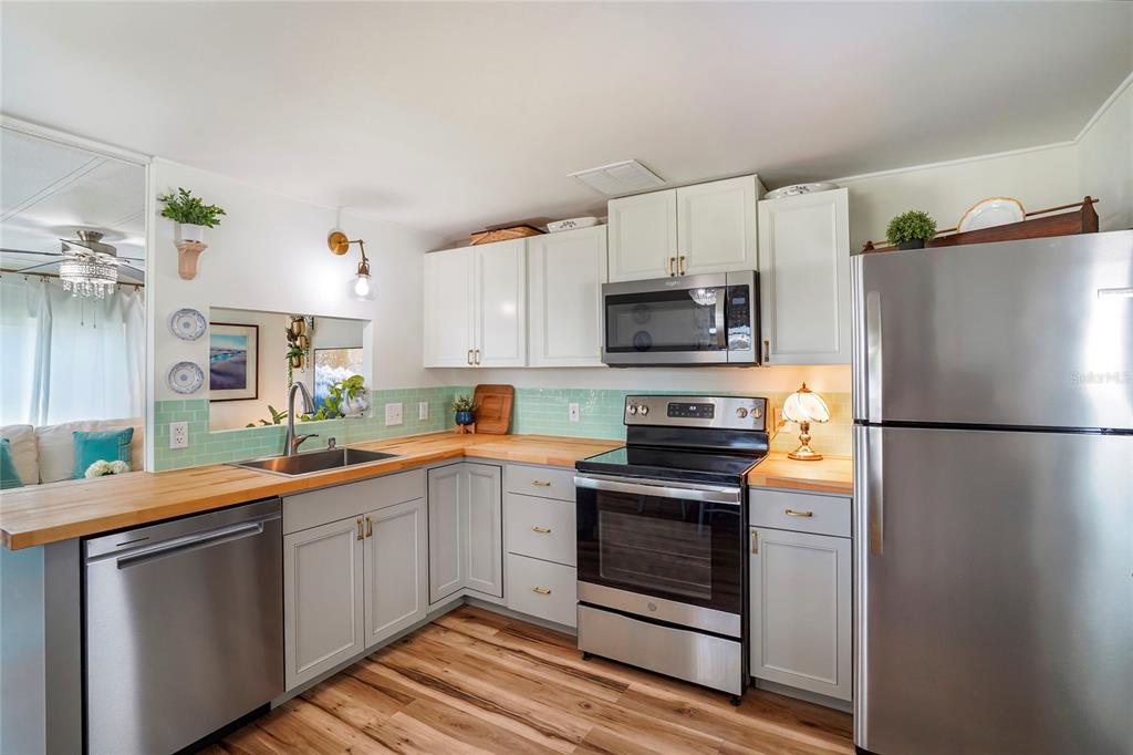 A kitchen features light gray cabinets, butcher block countertops, stainless steel appliances, and green tile — 512 IMPERIAL DRIVE, NORTH PORT, FL