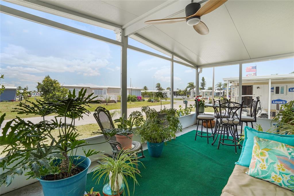 A screened-in porch features a green carpet, potted plants, patio furniture, and a ceiling fan — 512 IMPERIAL DRIVE, NORTH PORT, FL