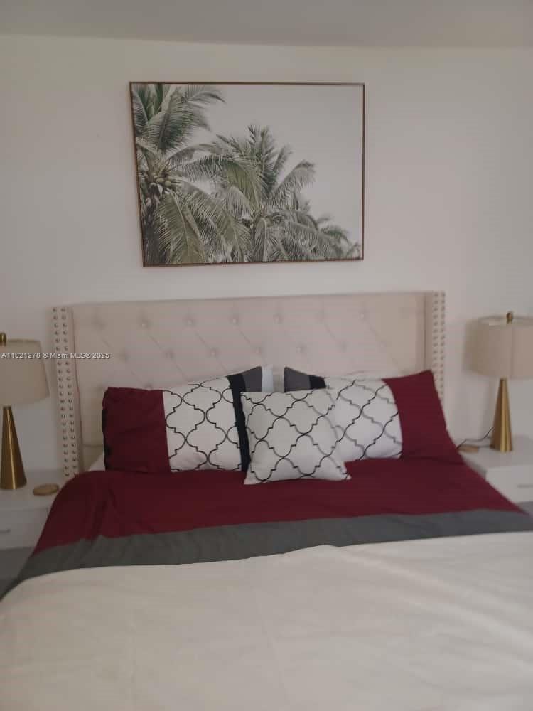 A bedroom features a tufted beige headboard, red and patterned pillows, and palm tree artwork — 322 Nebraska St # 1, Hollywood FL 33019, HOLLYWOOD, FL