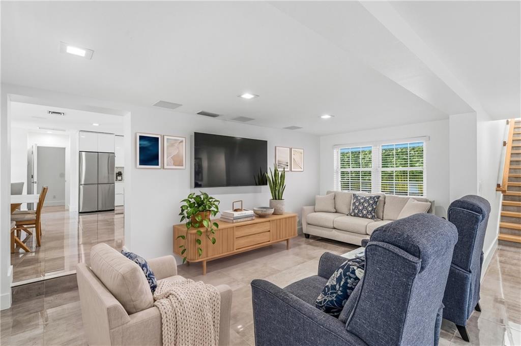 A living room features a wall-mounted television, a wooden media console, and neutral-toned furniture — VERO BEACH, FL