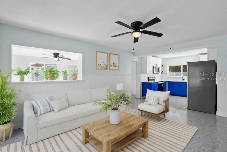 This living room features a white sofa, a wooden coffee table, and a blue kitchen — 675 182ND AVENUE E, REDINGTON SHORES, FL