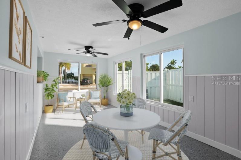 A sunroom features a dining set, ceiling fans, light blue walls, and large windows — 675 182ND AVENUE E, REDINGTON SHORES, FL
