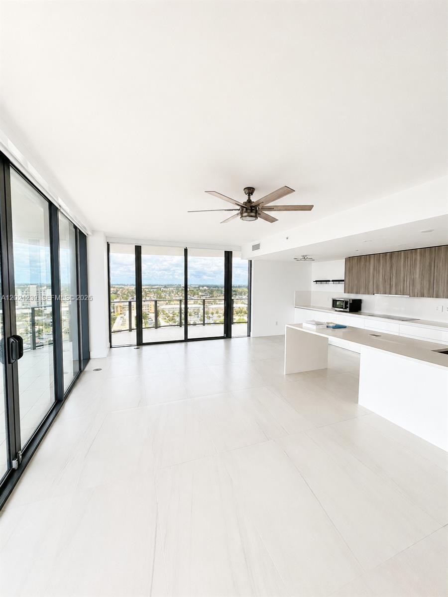 A modern open-concept kitchen and living area features white tile floors and floor-to-ceiling windows — 730 N Ocean Blvd # 1205, Pompano Beach FL 33062, POMPANO BEACH, FL