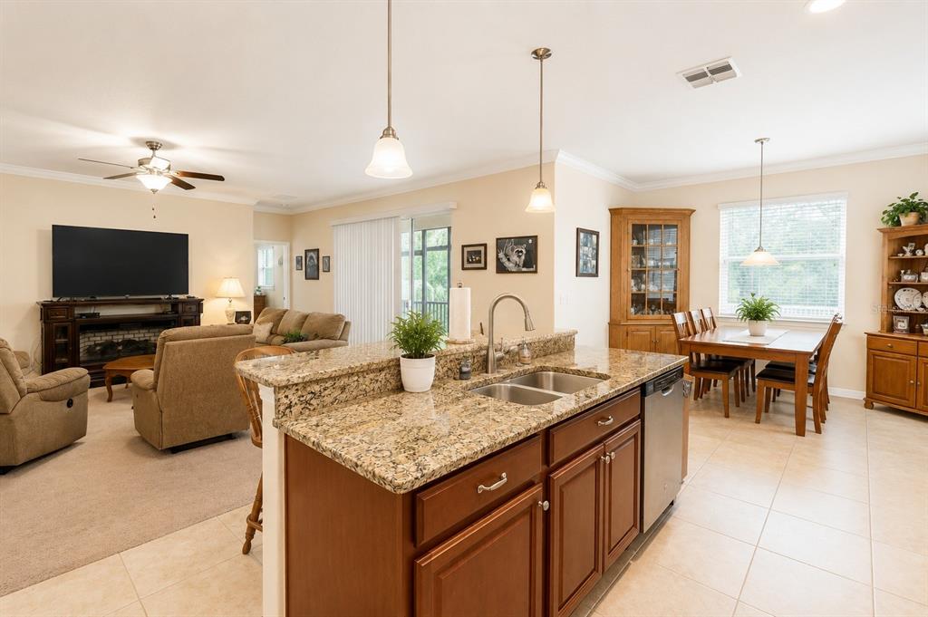 A kitchen island with granite countertops overlooks an open-concept living and dining area — 13842 BEE TREE COURT, HUDSON, FL