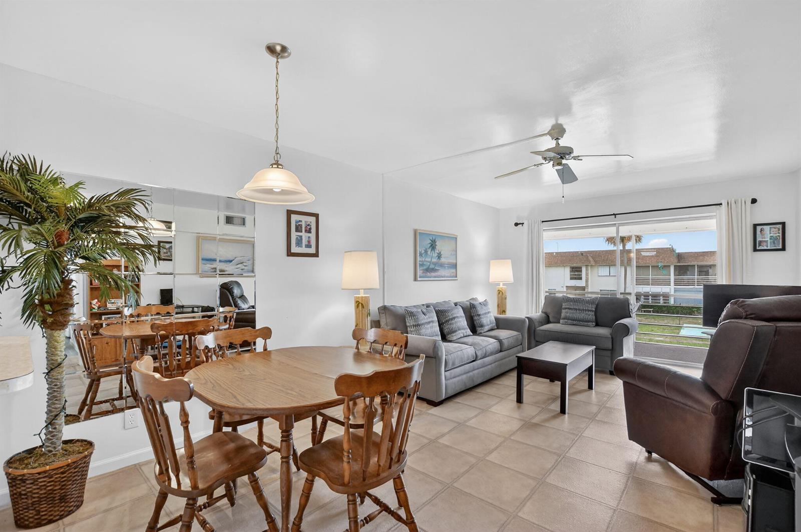 A living and dining area with tile floors, a wooden table, and a mirrored wall — 9855 Sandalfoot Boulevard Apt 317, Boca Raton FL 33428, BOCA RATON, FL
