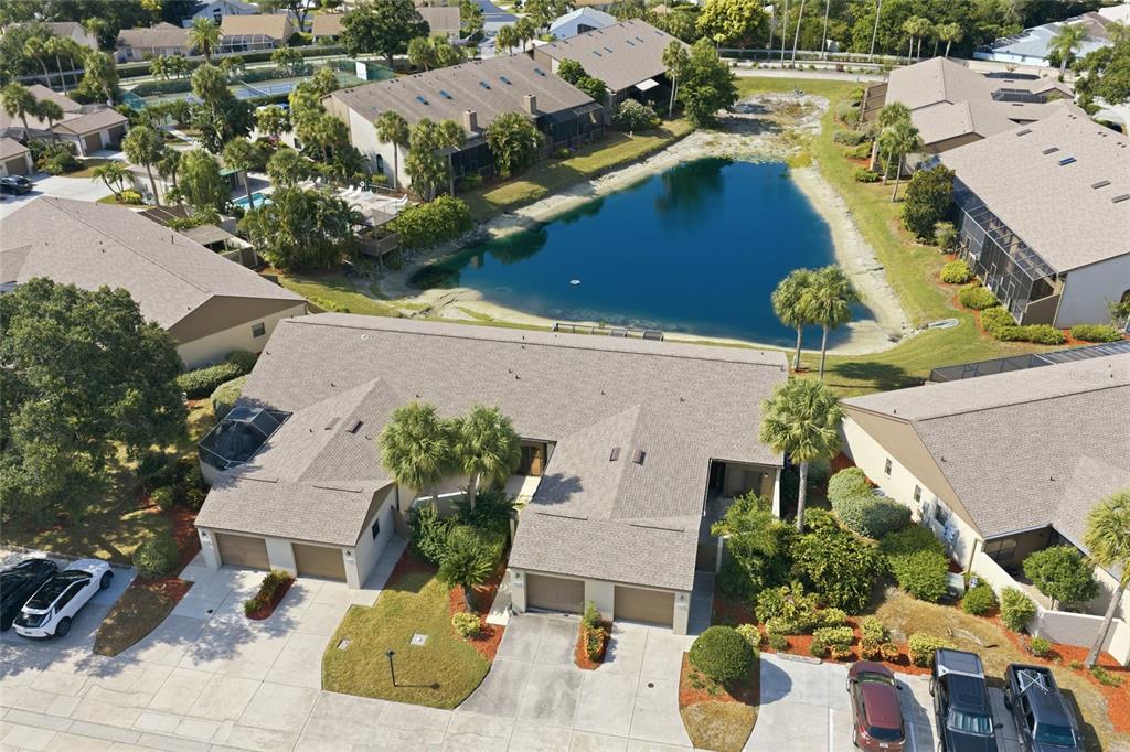 An aerial view shows a multi-unit residential building with attached garages next to a pond — 3446 BEEKMAN PLACE UNIT 50, SARASOTA, FL