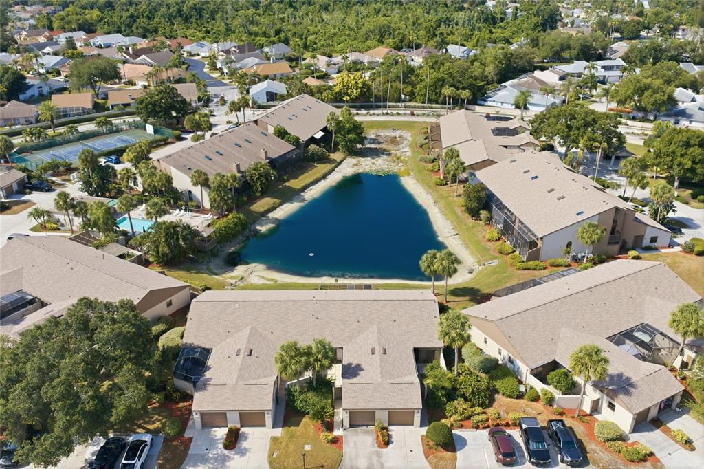 An aerial view shows a residential complex with townhouses surrounding a central pond — 3446 BEEKMAN PLACE UNIT 50, SARASOTA, FL