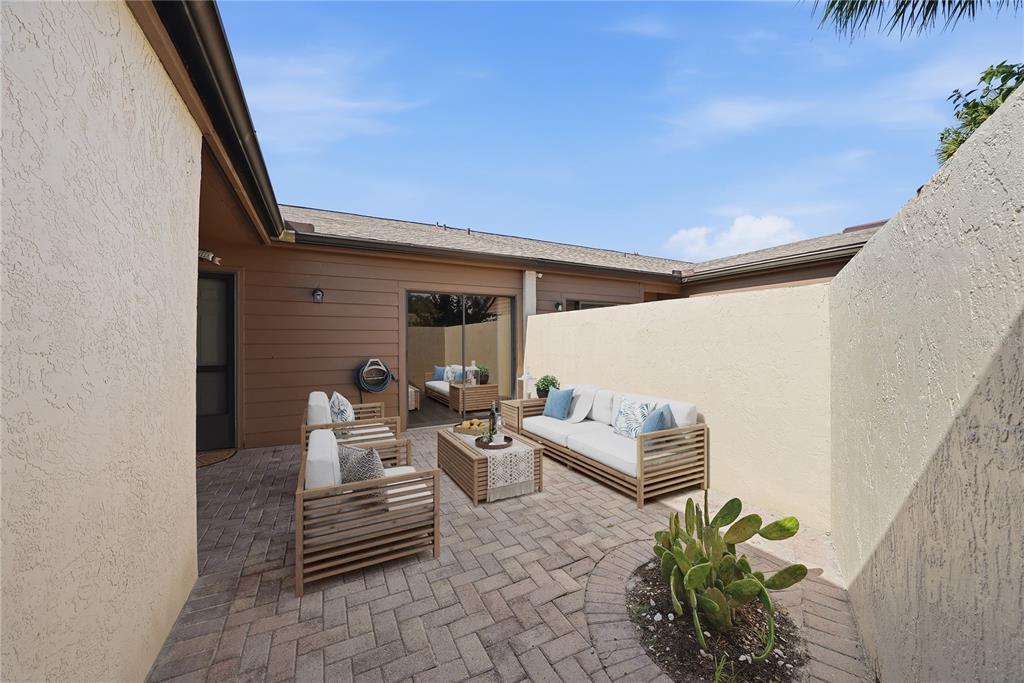 A paved courtyard features outdoor seating, a cactus garden, and a sliding glass door entrance — 3446 BEEKMAN PLACE UNIT 50, SARASOTA, FL