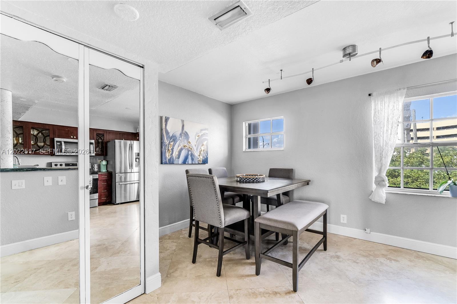 A dining area features a square table with chairs and a bench under track lighting — 349 Virginia St # 349, Hollywood FL 33019, HOLLYWOOD, FL