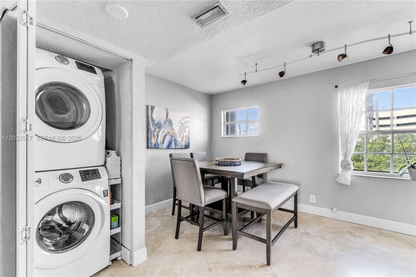 A dining area features a table with chairs and a bench next to a laundry closet — 349 Virginia St # 349, Hollywood FL 33019, HOLLYWOOD, FL