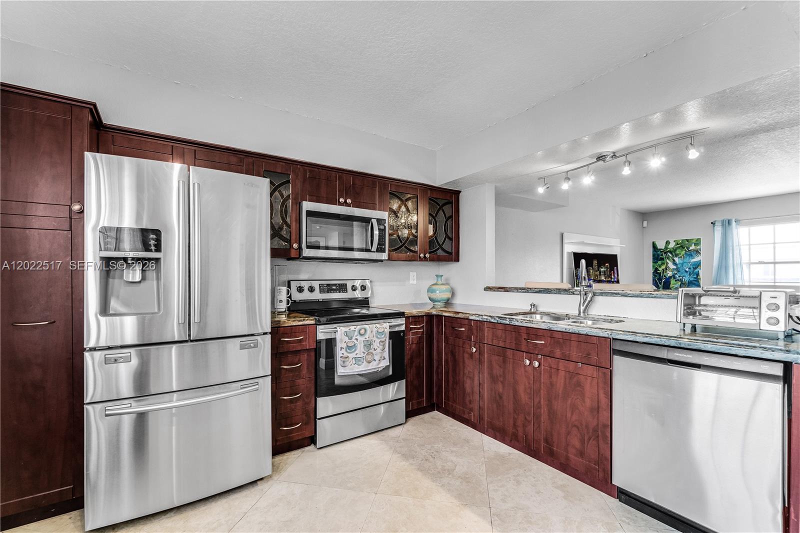 A kitchen features dark wood cabinets, stainless steel appliances, and a granite countertop — 349 Virginia St # 349, Hollywood FL 33019, HOLLYWOOD, FL