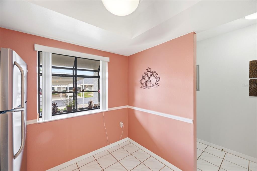 A kitchen nook with peach walls, white tile floors, and a window overlooking a carport — 7612 OAKMONT LANE, NEW PORT RICHEY, FL