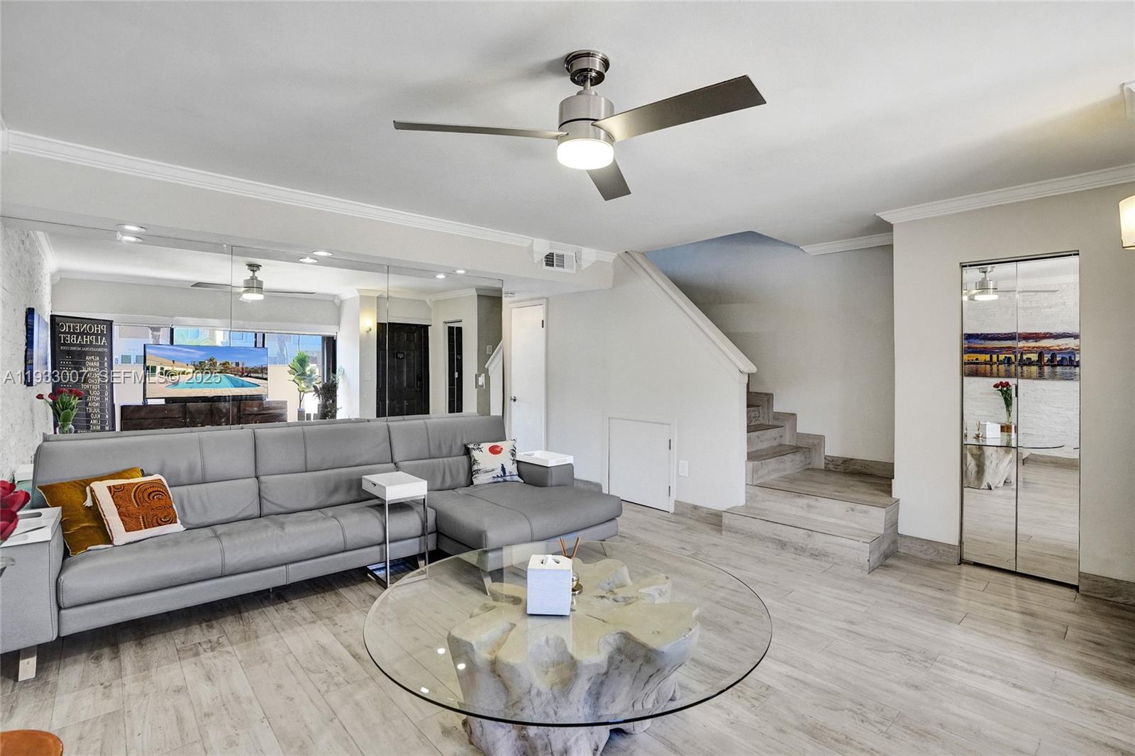 A living room features a gray sectional sofa, a glass coffee table, and a staircase — 16478 NE 27th Pl # 34, Eastern Shores FL 33160, EASTERN SHORES, FL