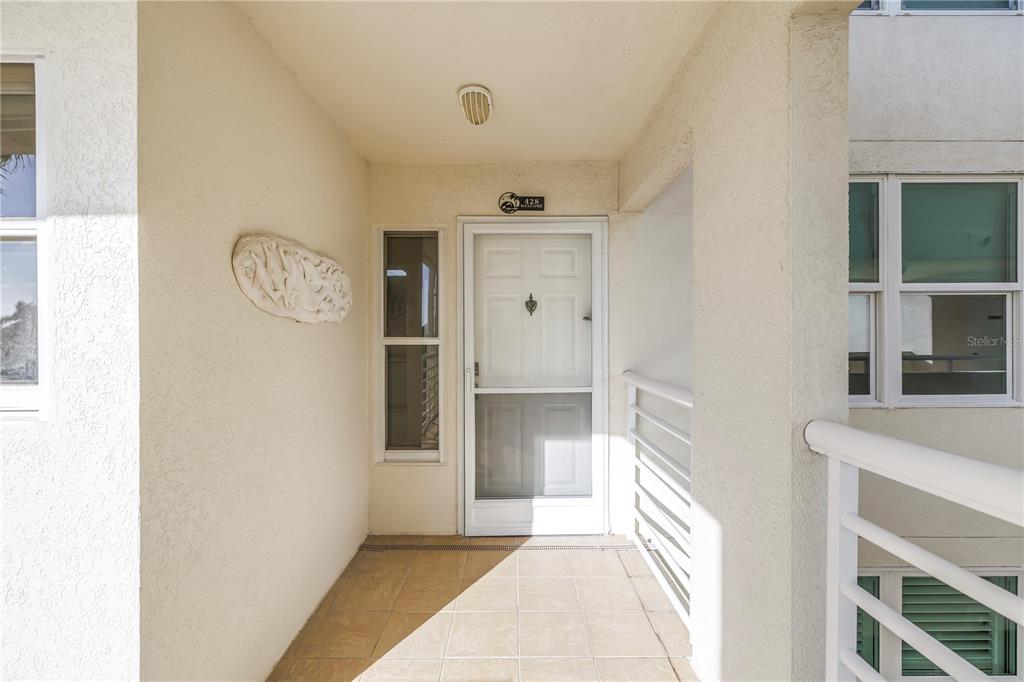 A covered entryway features a tiled floor, a white front door, and a side window — 6001 BAHIA DEL MAR CIRCLE UNIT 428, ST PETERSBURG, FL