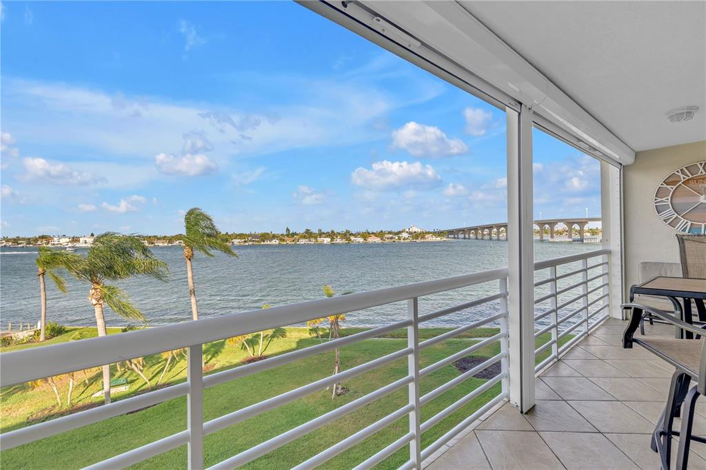 A balcony with white railings overlooks a grassy lawn, a bay, and a distant bridge — 6001 BAHIA DEL MAR CIRCLE UNIT 428, ST PETERSBURG, FL
