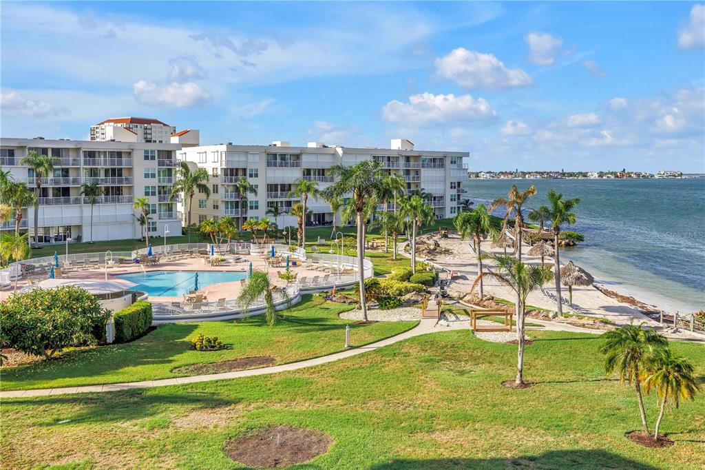 An outdoor view of a multi-story apartment building, swimming pool, and beach along the water — 6001 BAHIA DEL MAR CIRCLE UNIT 428, ST PETERSBURG, FL