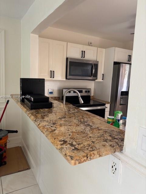 A kitchen features white cabinets, granite countertops, and stainless steel appliances — 6101 N Falls Circle Dr # 312, Lauderhill FL 33319, LAUDERHILL, FL