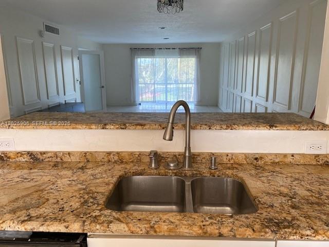 A kitchen sink with a granite countertop overlooks an open living area with white walls — 6101 N Falls Circle Dr # 312, Lauderhill FL 33319, LAUDERHILL, FL