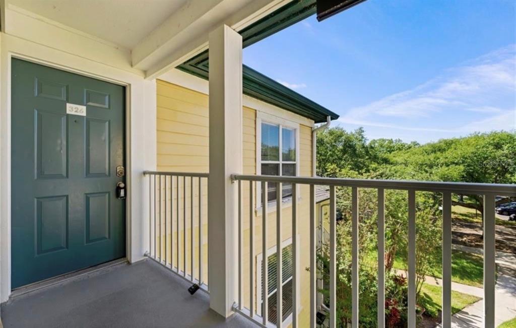 A balcony with a green door, white railing, and a view of trees and parking — 4107 CHATHAM OAK COURT UNIT 326, TAMPA, FL