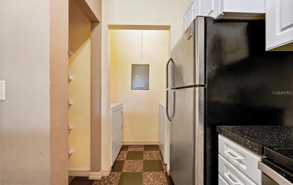 A kitchen with a stainless steel refrigerator leads to a laundry area with tiled floors — 4107 CHATHAM OAK COURT UNIT 326, TAMPA, FL
