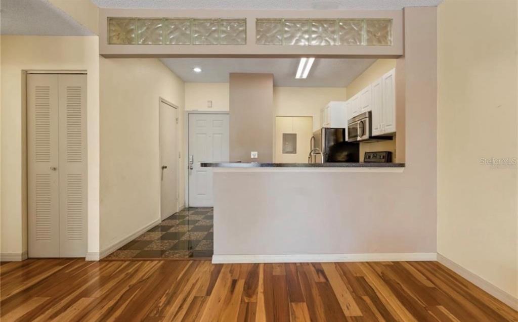A kitchen with white cabinets and a breakfast bar overlooks a room with wood flooring — 4107 CHATHAM OAK COURT UNIT 326, TAMPA, FL