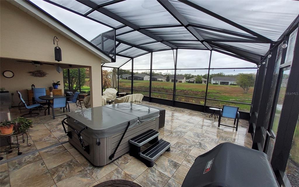 A covered patio features a hot tub, tiled flooring, and a view of the landscape — 26657 MANASSAS DRIVE, LEESBURG, FL