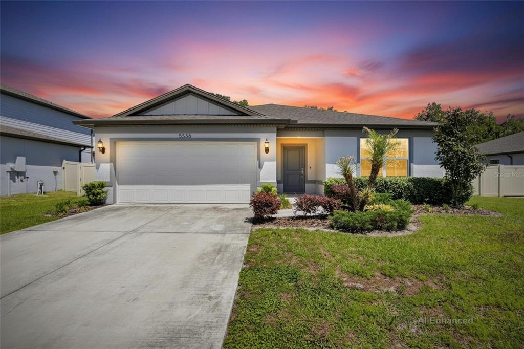 A single-story suburban house with a two-car garage and a concrete driveway at sunset — 5536 KEATON SPRINGS DRIVE, LAKELAND, FL