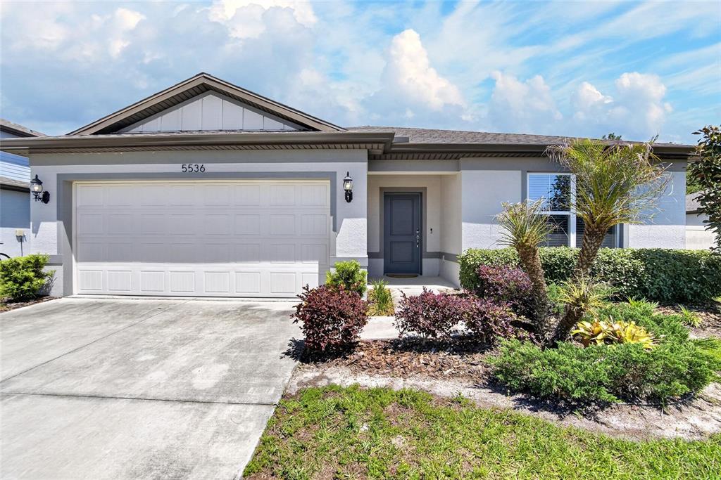 A single-story house with a white garage, gray door, and landscaped front yard — 5536 KEATON SPRINGS DRIVE, LAKELAND, FL