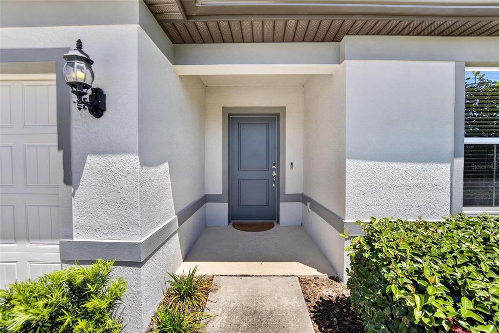 A gray front door is centered in a recessed entryway with a concrete walkway — 5536 KEATON SPRINGS DRIVE, LAKELAND, FL