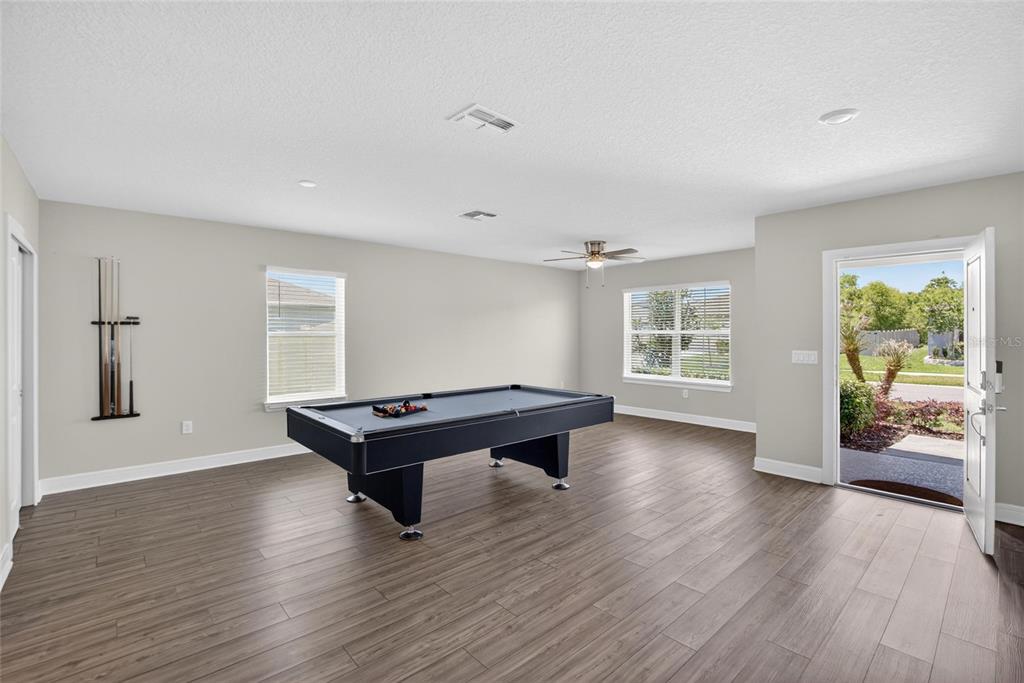 A game room with a pool table, wood-look flooring, and an open exterior door — 5536 KEATON SPRINGS DRIVE, LAKELAND, FL
