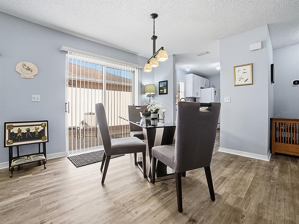 A dining area features a glass table, four grey chairs, and a sliding glass door — 1202 FERNANDO LANE, LADY LAKE, FL