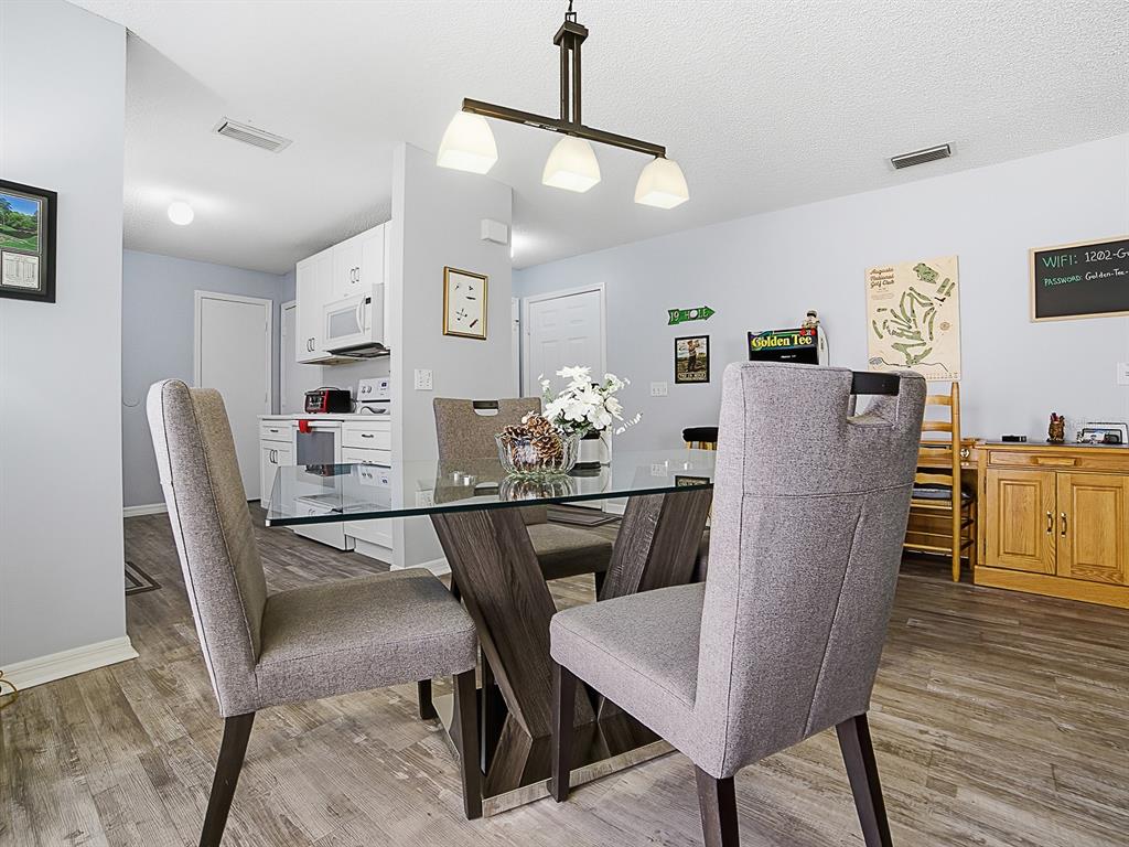 A dining area features a glass-top table, gray upholstered chairs, and a modern light fixture — 1202 FERNANDO LANE, LADY LAKE, FL