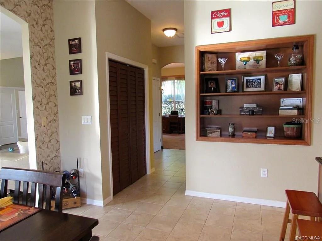 A spacious living room features dark hardwood floors, a ceiling fan, and sliding glass doors — 13038 PASTORE COURT, SPRING HILL, FL