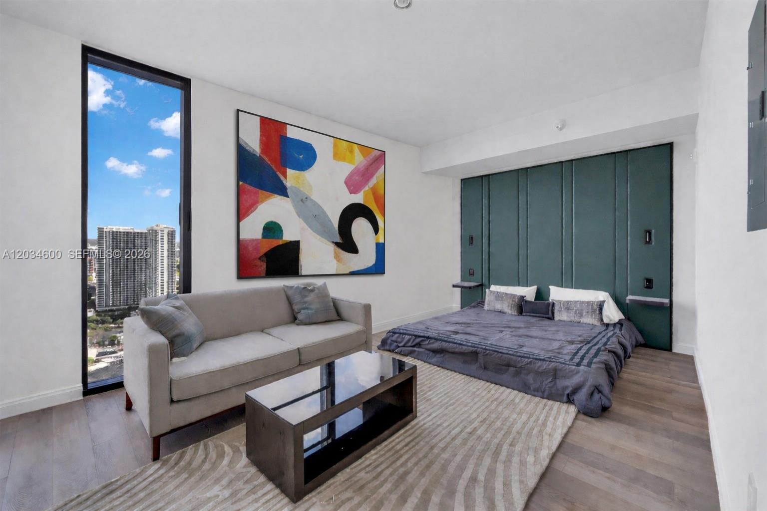 A bedroom features a low-profile bed against a green paneled wall and a gray sofa — 20 NE 11th ST # 2803A, Miami FL 33132, MIAMI, FL