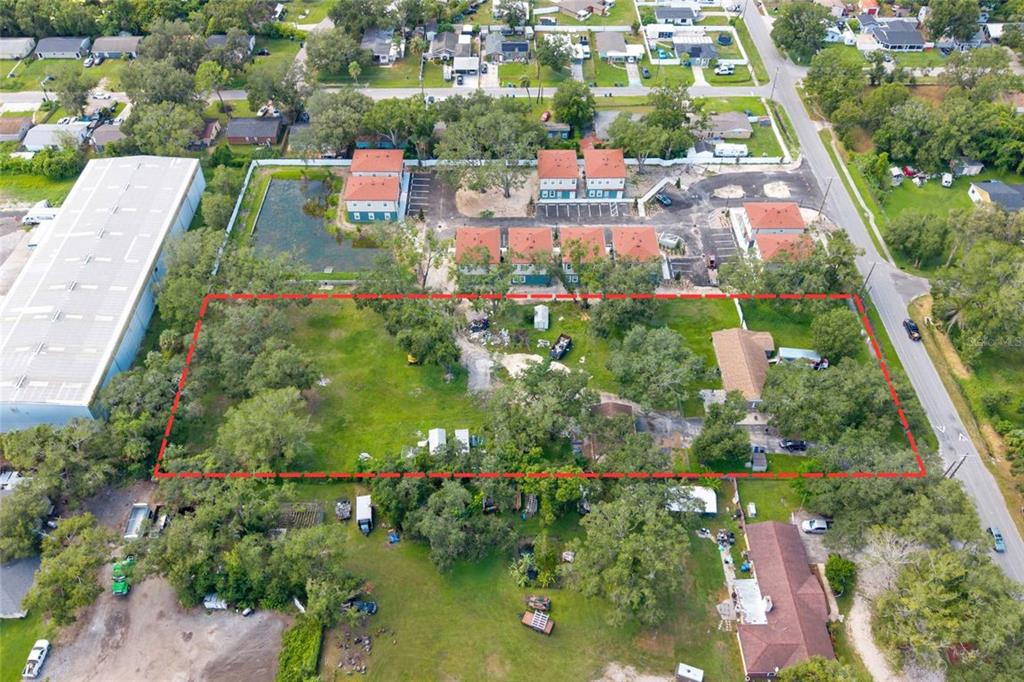 An aerial view shows a rectangular plot of land outlined in red with trees and structures — 7201 E 21ST AVENUE, TAMPA, FL