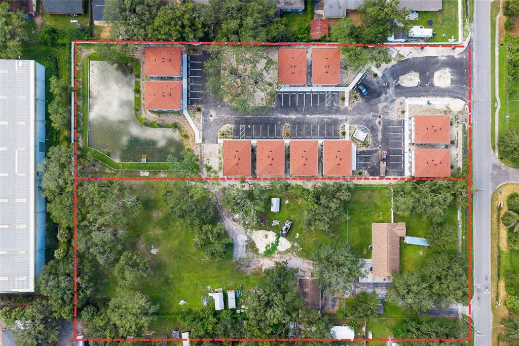 An aerial view shows a residential complex with multiple buildings, a pond, and parking areas — 7201 E 21ST AVENUE, TAMPA, FL