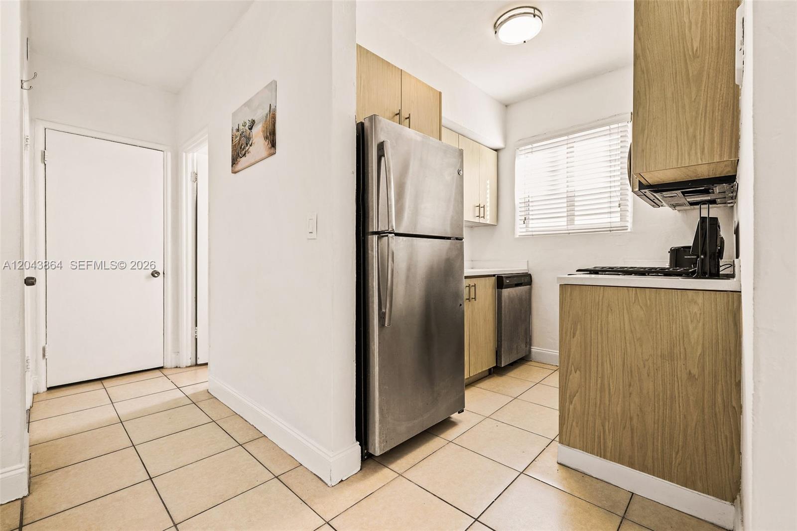 A kitchen features stainless steel appliances, light wood cabinets, and beige tile flooring — 7340 Harding Ave # 16, Miami Beach FL 33141, MIAMI BEACH, FL