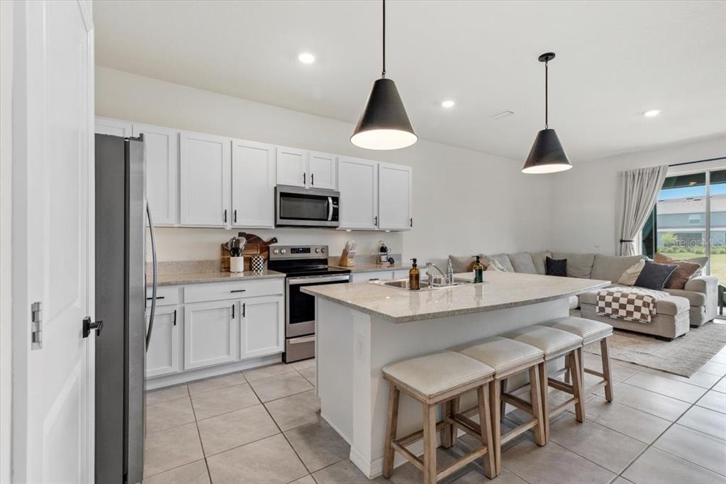 A kitchen with white cabinets, granite countertops, and an island with bar seating — 33064 TULIP PETAL LANE, WESLEY CHAPEL, FL