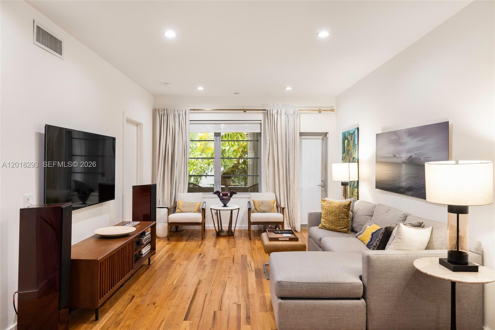 A living room features a gray sectional sofa, wood media console, and two accent chairs — 1551 Lenox Ave # 8, Miami Beach FL 33139, MIAMI BEACH, FL