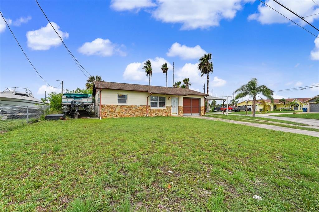 A single-story house with stone siding, a garage, and a boat parked in the yard — 4093 FLAMINGO BOULEVARD, HERNANDO BEACH, FL