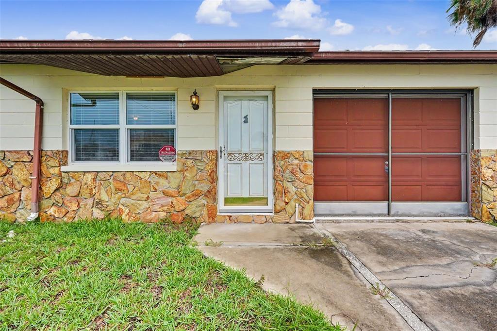 The exterior of a single-story home features a stone facade, a front door, and a garage — 4093 FLAMINGO BOULEVARD, HERNANDO BEACH, FL