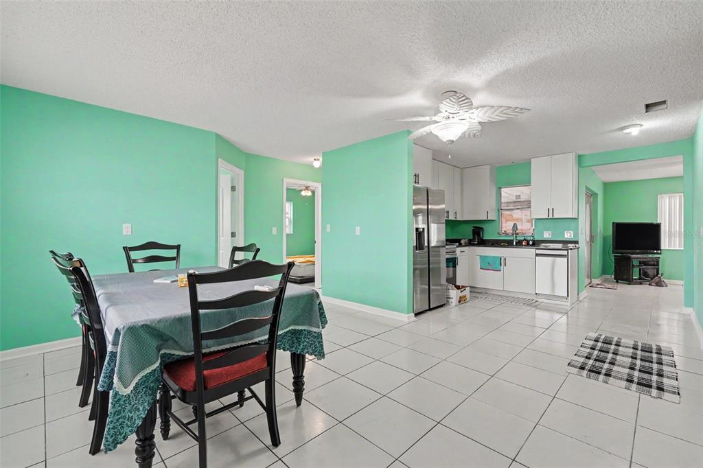 An open-concept kitchen and dining area features mint green walls and white tile flooring — 4093 FLAMINGO BOULEVARD, HERNANDO BEACH, FL