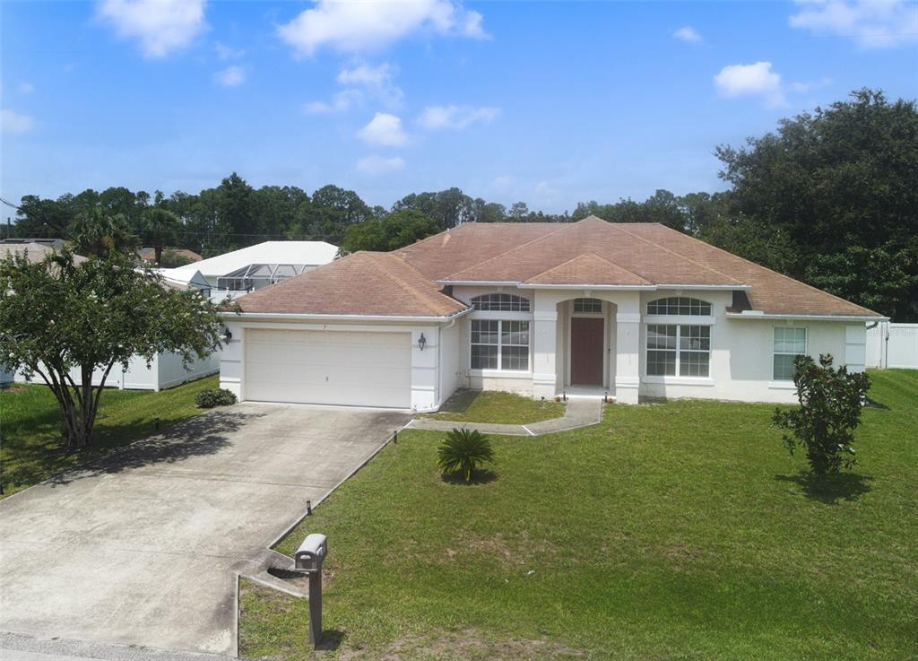 An exterior view of a single-story house with a tan roof and a concrete driveway — 7 PHOENIX LANE, PALM COAST, FL