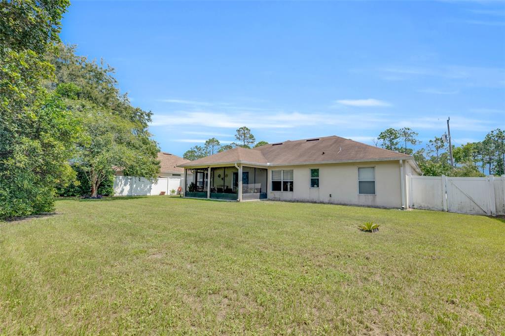 The exterior view shows a house with a screened-in porch and a large grassy backyard — 7 PHOENIX LANE, PALM COAST, FL