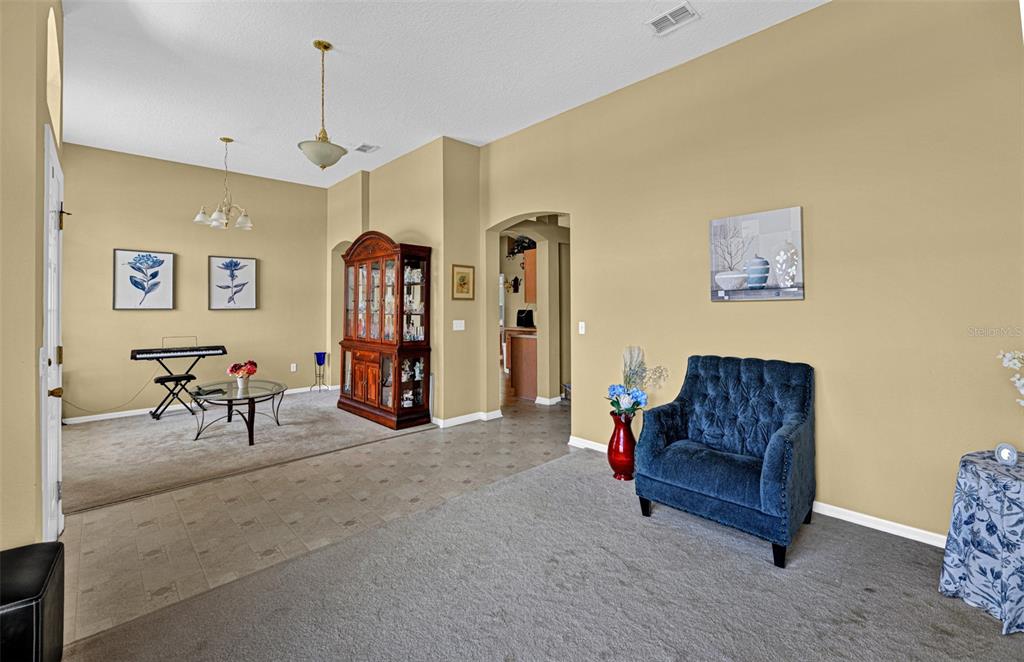 A living and dining area features beige walls, carpeted floors, a blue armchair, and a hutch — 7 PHOENIX LANE, PALM COAST, FL